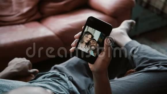 非洲男性使用智能手机与白人女友自拍一对多种族的夫妇笑着看照片视频的预览图