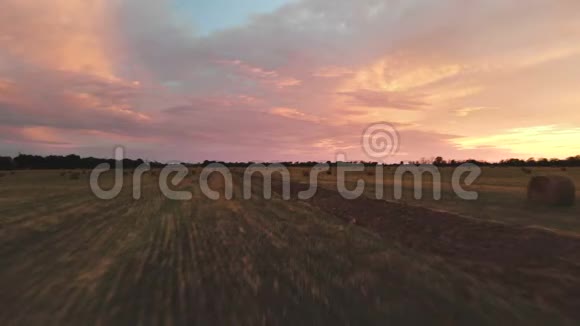 金色的多色日落在一个农场的田野和干草捆黄昏时分飞行的无人机飞过一片割草的麦田低键4k视频的预览图