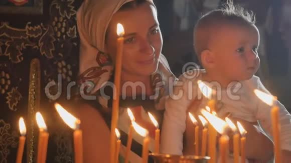 母亲和小儿子观察教堂里燃烧的蜡烛视频的预览图