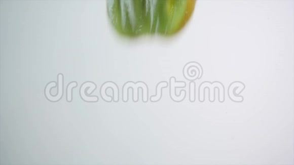 猕猴桃片落入水中猕猴桃在白色背景下的水滴新鲜猕猴桃视频的预览图