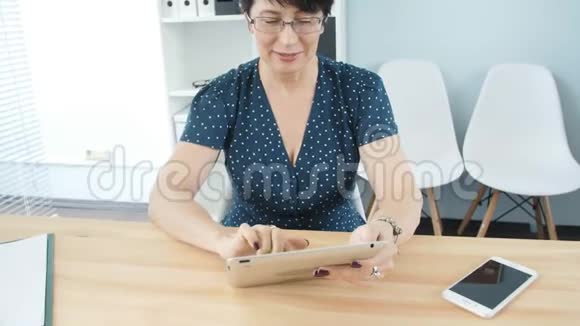 办公室里一个中年妇女用平板电脑视频的预览图