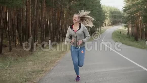 女运动员沿着松树沿着乡村道路奔跑视频的预览图