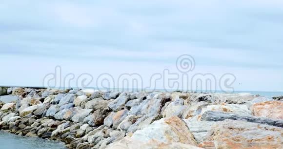 阴天有石头和冲浪的风景海岸线视频的预览图