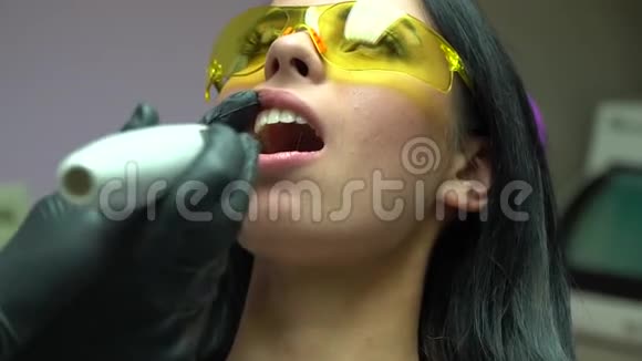 牙医使用紫外线灯对病人牙齿牙科手术现场一个黄色病人的特写肖像视频的预览图