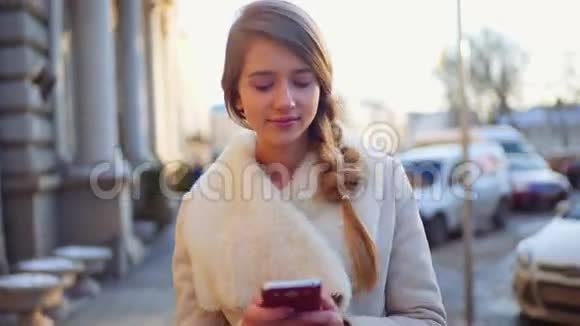 年轻漂亮的金发女郎走在街上环顾四周通过电话交流有很多人视频的预览图