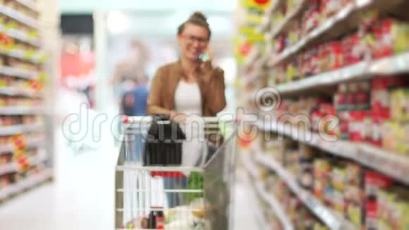 一个年轻的现代女孩正在超市购物用手机聊天真诚的微笑超市手推车是视频的预览图