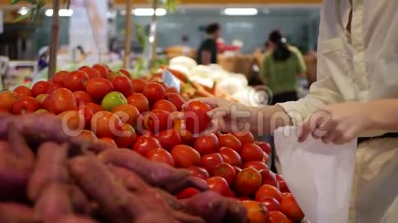 女人的手把西红柿放进超市的包裹里视频的预览图