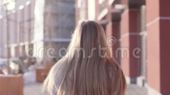 美丽的年轻女子她的头发松散地走过一座现代建筑转向相机微笑视频的预览图