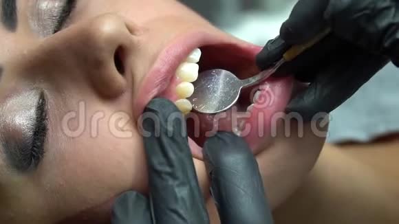 在牙科诊所牙医用镜子检查年轻女人的牙齿专业照明视频的预览图