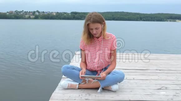 女人正在用平板电脑在湖边慢动作打电话视频的预览图