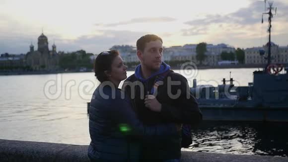 一对相爱的夫妻站在海滩上靠近城市的河流亲吻慢动作1920x1080全高清视频的预览图
