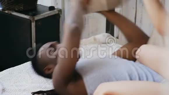 多种族夫妇在床上的近景靠枕头打架女人坐在男人身上一起玩笑视频的预览图