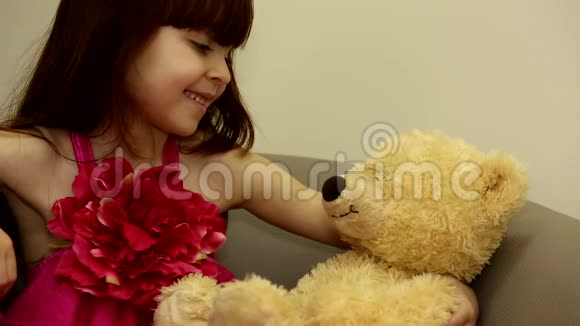 小可爱快乐女孩平静孩子玩着舌头慈爱地看着她的大毛绒玩具在椅子上视频的预览图