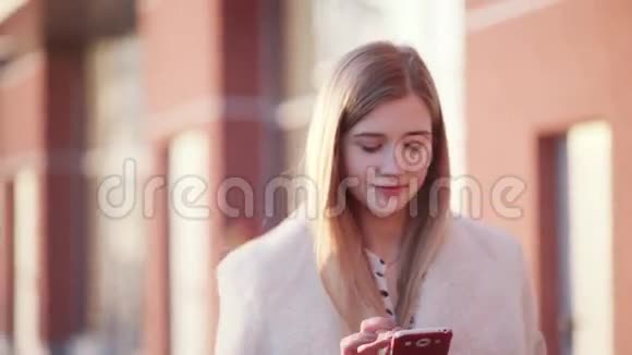 年轻漂亮的商务女性用手机打电话给她的朋友一边笑着走过一栋现代建筑视频的预览图
