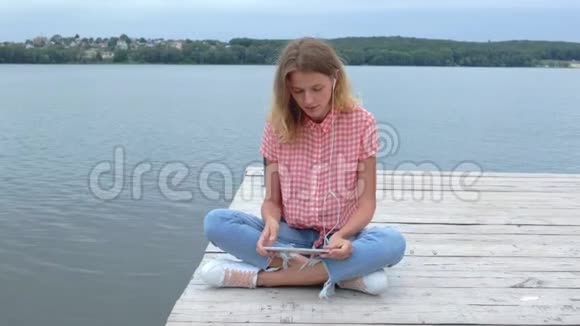 女人在湖边的平板电脑上轻敲轻挥视频的预览图