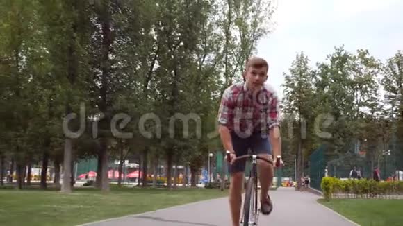 在公园路上骑着一辆老式自行车的年轻英俊男子的肖像运动的家伙在户外骑自行车健康活动视频的预览图