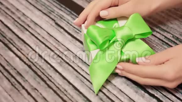 女士双手解开礼盒上的绿色丝带木制桌子上放着一双柔软的女性手打开行李视频的预览图