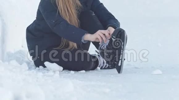 坐在雪地上收紧溜冰鞋带的少女视频的预览图