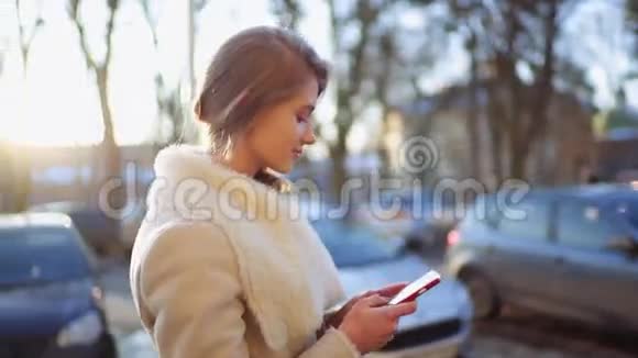 年轻漂亮的金发女郎正在她的智能手机上打字走在繁忙的街道上路过美好的文艺复兴时期视频的预览图