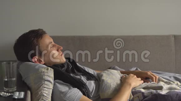 生病的男人躺在床上在家里吃药视频的预览图