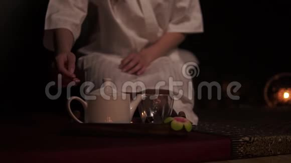 美丽的黑发女人穿着浴袍拿着茶壶喝着可怜的茶在水疗中心慢动作地喝着草药茶泰国视频的预览图