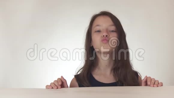 美丽淘气的少女快乐地在白色背景的股票视频上向空中发送吻视频的预览图
