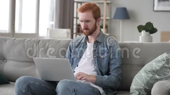 失落沮丧的创意胡子人在笔记本电脑上工作视频的预览图