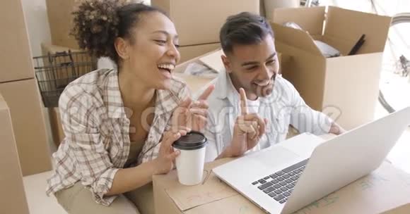 快乐的混血夫妻讨论使用笔记本电脑视频的预览图