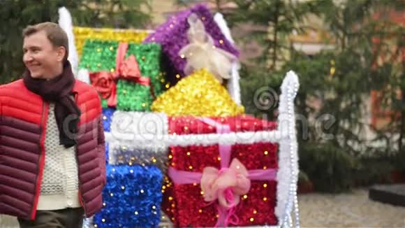 一个男人和一个女人牵着手在圣诞市场上用五颜六色的包裹礼物路过圣诞老人A视频的预览图