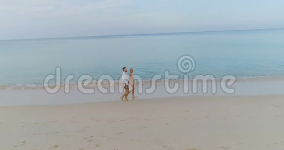 阳光明媚的暑假里一对年轻的快乐夫妇在热带海滩上喝果汁视频的预览图