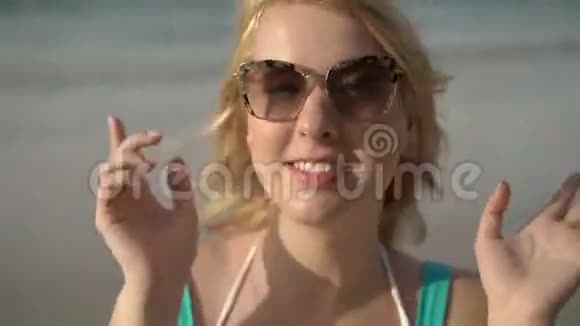 年轻的金发女郎在沙滩上跳特写视频的预览图