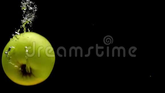 黄色红色和绿色的苹果落在黑色背景的透明水中视频的预览图