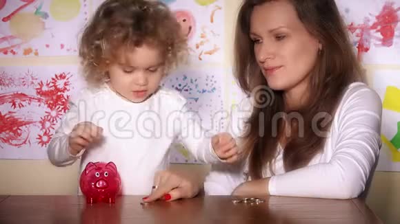 保姆和可爱的小女孩把硬币放进储蓄罐视频的预览图