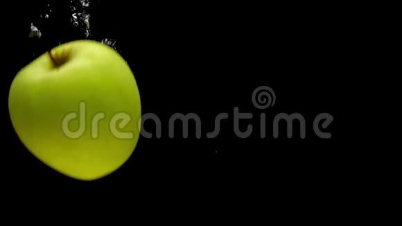 黄色红色和绿色的苹果落入黑色背景的透明水中视频的预览图