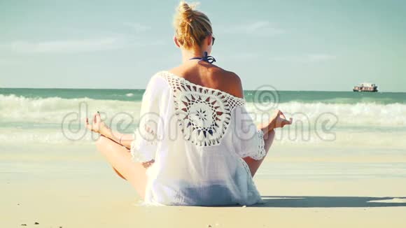 年轻的金发女人在海滩上做瑜伽视频的预览图