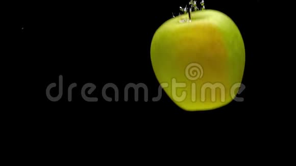 黄色和红色的苹果在黑色的背景下落入透明的水中视频的预览图