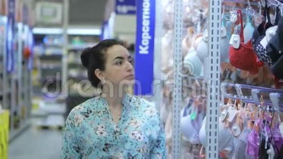 漂亮的黑发女士选择内衣在商店漂亮的女人在超市里考虑胸罩漂亮女人视频的预览图