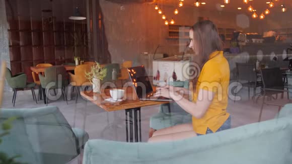 自由职业者使用智能手机笔记本电脑在咖啡馆短信分享社交媒体视频的预览图