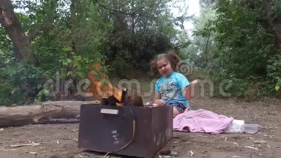 女童子军燃烧坐在木头上燃烧着篝火旅游视频的预览图