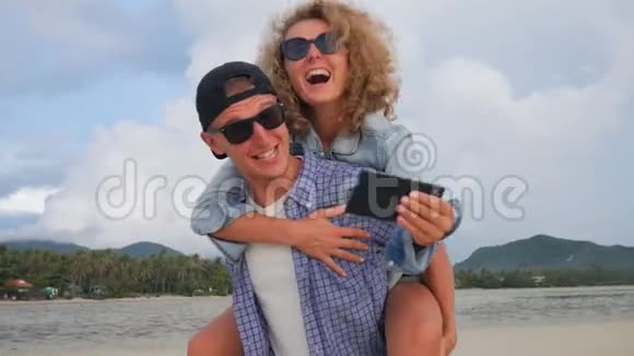 快乐的年轻夫妇爱在海滩上做猪背自拍在男朋友后面玩的女孩泰国视频的预览图