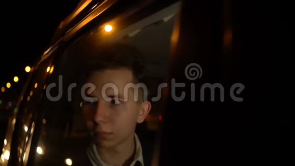 年轻英俊的少年在夜间城市和司机一起乘坐出租车旅行的肖像4k个镜头视频的预览图