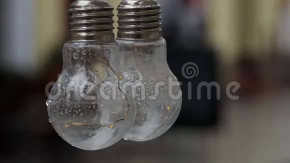 两个灯泡悬挂在户外的街道上在雨天缓慢运动视频的预览图