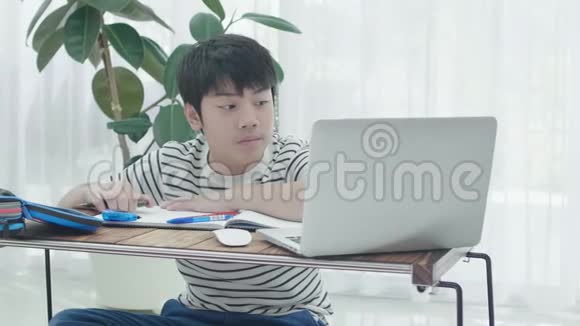 亚洲青少年男孩在家用笔记本电脑做作业视频的预览图