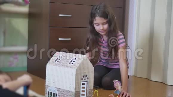女孩在玩具屋里玩玩具坐在地板上在室内视频的预览图