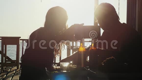 年轻漂亮的情侣自拍智能手机休息户外海滩咖啡馆喝啤酒在惊人的日落视频的预览图