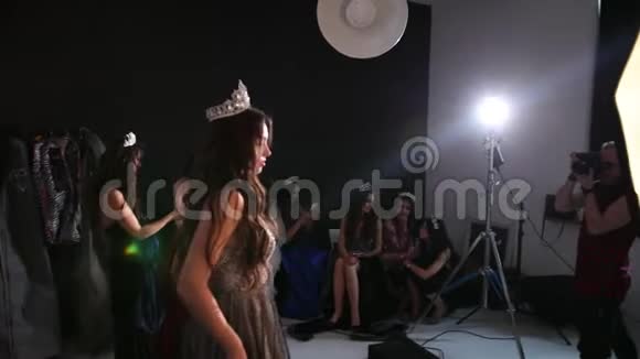 布鲁内特女孩穿着闪亮的连衣裙戴着皇冠在工作室拍照视频的预览图