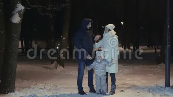 晚上冬季公园晚上和女儿拥抱的幸福夫妻视频的预览图