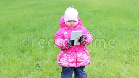 穿着暖和的衣服的小女孩站在草地上脸上挂着白色的药片视频的预览图