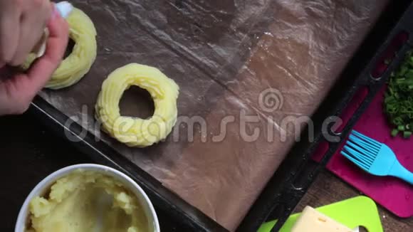 一个女人在烤盘上形成土豆泥戒指借助糕点包旁边的其他烹饪原料视频的预览图