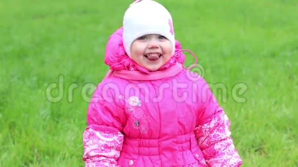 穿暖和衣服的小女孩站在草地上微笑着笑视频的预览图